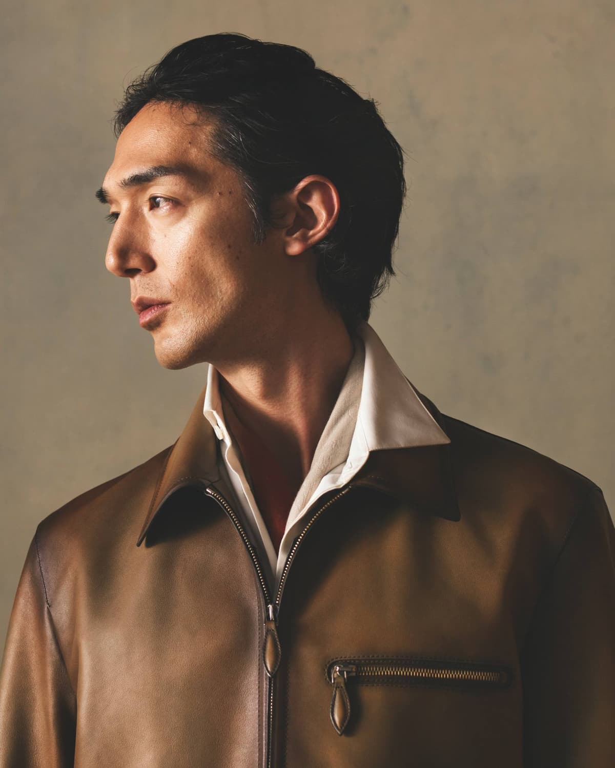 Model wearing a brown patinated Berluti leather jacket over an open-collar white shirt, part of Berluti Fall/Winter 2026 collection.