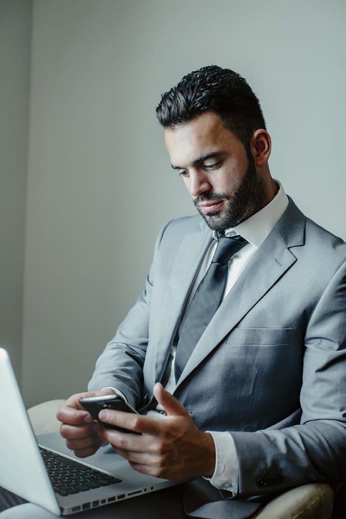Businessman using laptop and cell phone in armchair